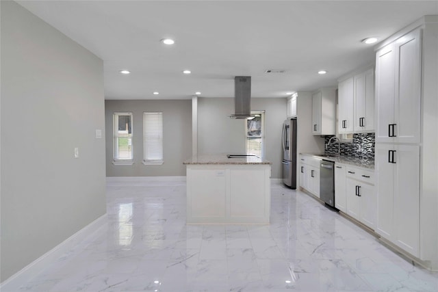 kitchen featuring white cabinets, backsplash, appliances with stainless steel finishes, island range hood, and light stone counters