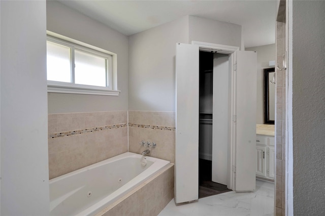 bathroom featuring vanity and tiled bath