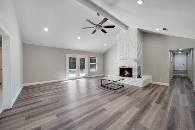 unfurnished living room featuring a fireplace, french doors, hardwood / wood-style floors, ceiling fan, and beamed ceiling