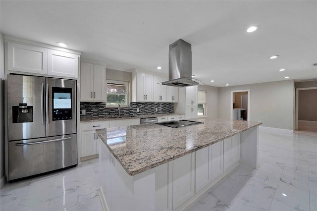 kitchen with island exhaust hood, a kitchen island, stainless steel appliances, white cabinets, and light stone counters