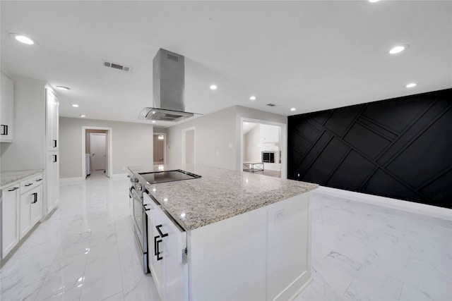 kitchen with white cabinetry, light stone countertops, a center island, and exhaust hood