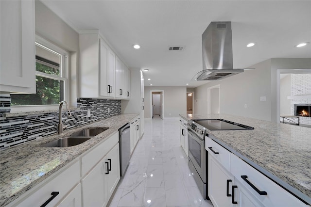 kitchen featuring light stone countertops, appliances with stainless steel finishes, sink, island exhaust hood, and white cabinets