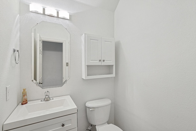 bathroom featuring vanity, toilet, and a textured ceiling