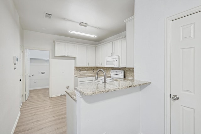 kitchen featuring light hardwood / wood-style floors, backsplash, white cabinets, light stone counters, and white appliances