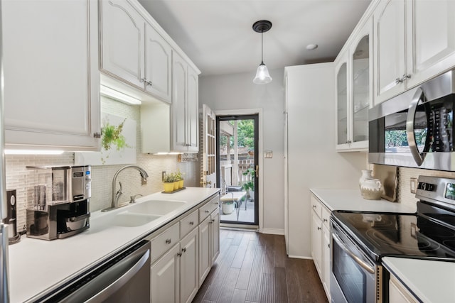 kitchen with white cabinets, appliances with stainless steel finishes, dark wood-type flooring, pendant lighting, and sink