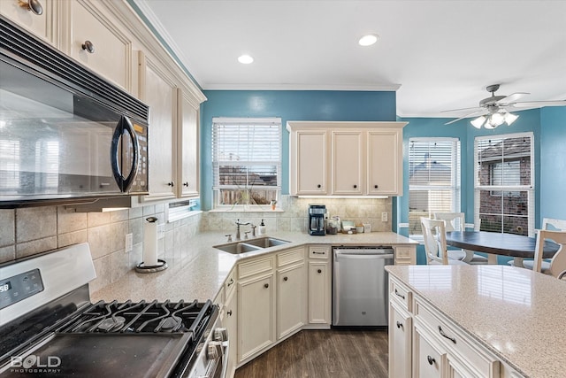 kitchen featuring sink, appliances with stainless steel finishes, ornamental molding, cream cabinets, and backsplash