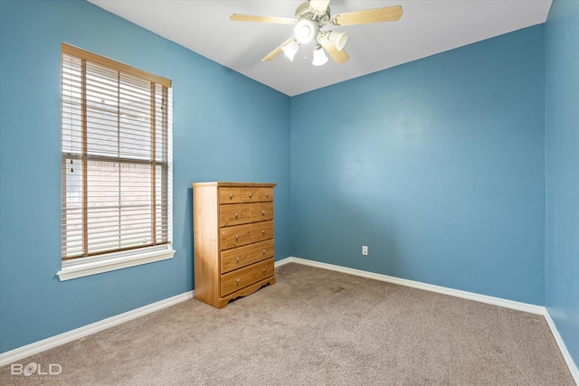 empty room with a wealth of natural light, light colored carpet, and ceiling fan