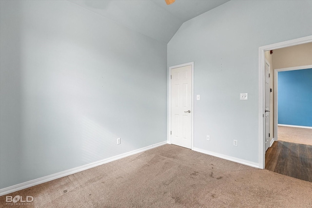 empty room with lofted ceiling and dark colored carpet