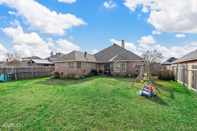 rear view of house featuring a yard and a playground