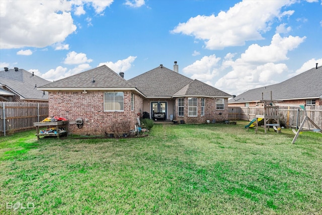 rear view of house featuring a playground and a lawn