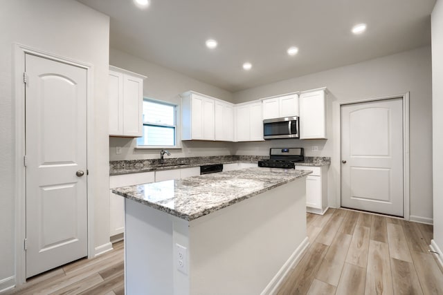 kitchen featuring appliances with stainless steel finishes, white cabinets, sink, and a kitchen island