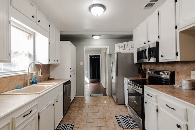 kitchen featuring backsplash, sink, appliances with stainless steel finishes, and white cabinets