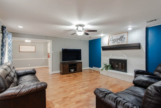 living room featuring ceiling fan, crown molding, a brick fireplace, and hardwood / wood-style floors