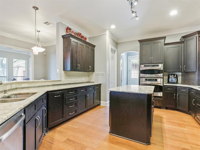 kitchen with appliances with stainless steel finishes, light hardwood / wood-style flooring, pendant lighting, dark brown cabinetry, and sink