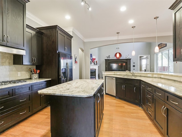 kitchen with light wood-type flooring, a kitchen island, dark brown cabinets, stainless steel appliances, and decorative light fixtures