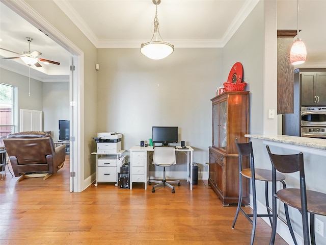 office area with ornamental molding, light wood-type flooring, and ceiling fan