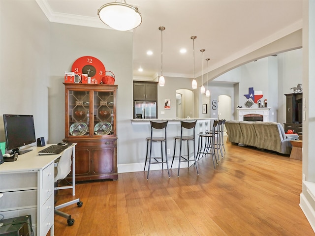 kitchen with light wood-type flooring, stainless steel fridge with ice dispenser, decorative light fixtures, crown molding, and a breakfast bar