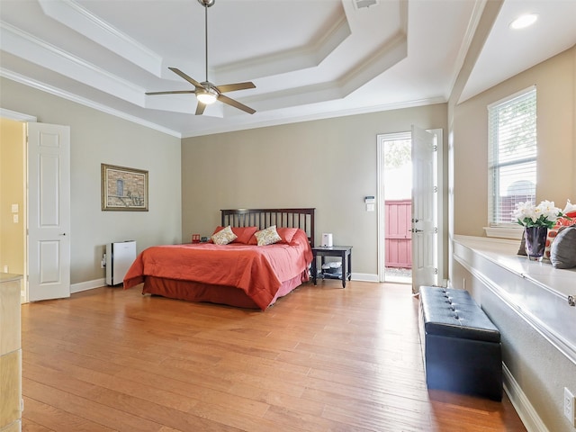 bedroom featuring light hardwood / wood-style floors, crown molding, a raised ceiling, and ceiling fan