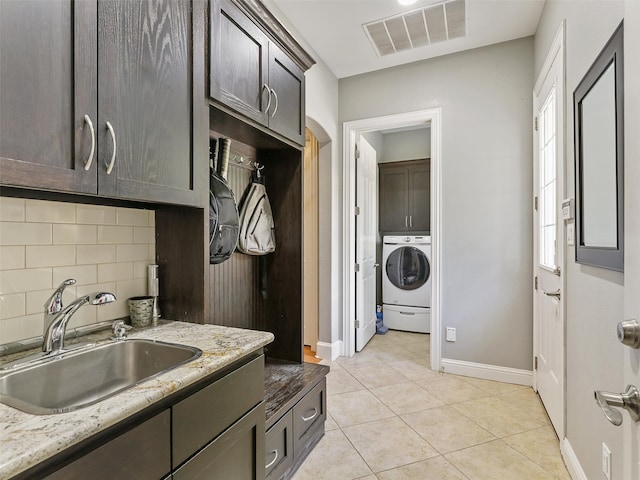 kitchen featuring dark brown cabinetry, washer / clothes dryer, tasteful backsplash, and sink