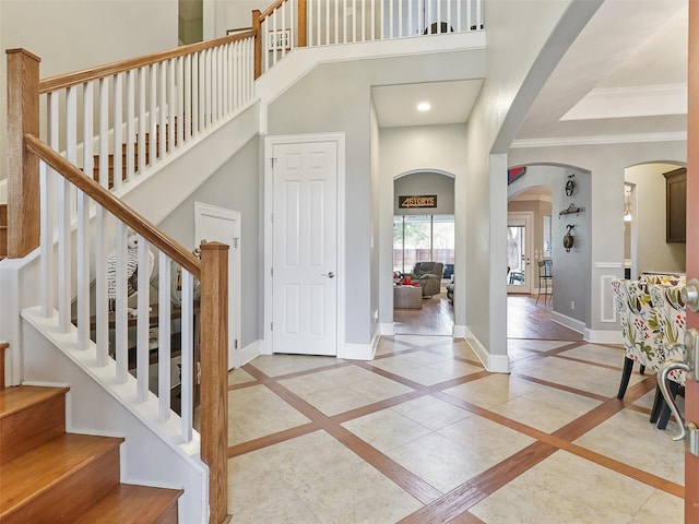 foyer featuring ornamental molding, a high ceiling, and light hardwood / wood-style floors