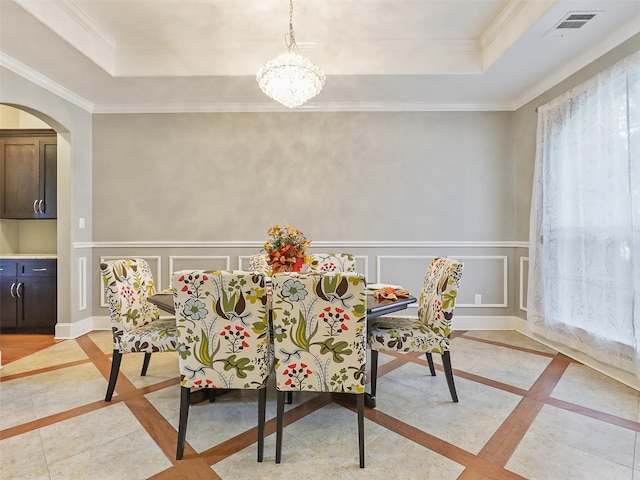 dining room with crown molding, a raised ceiling, and a chandelier