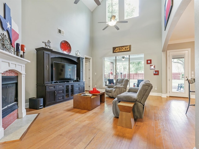 living room with ornamental molding, a high ceiling, hardwood / wood-style flooring, and ceiling fan