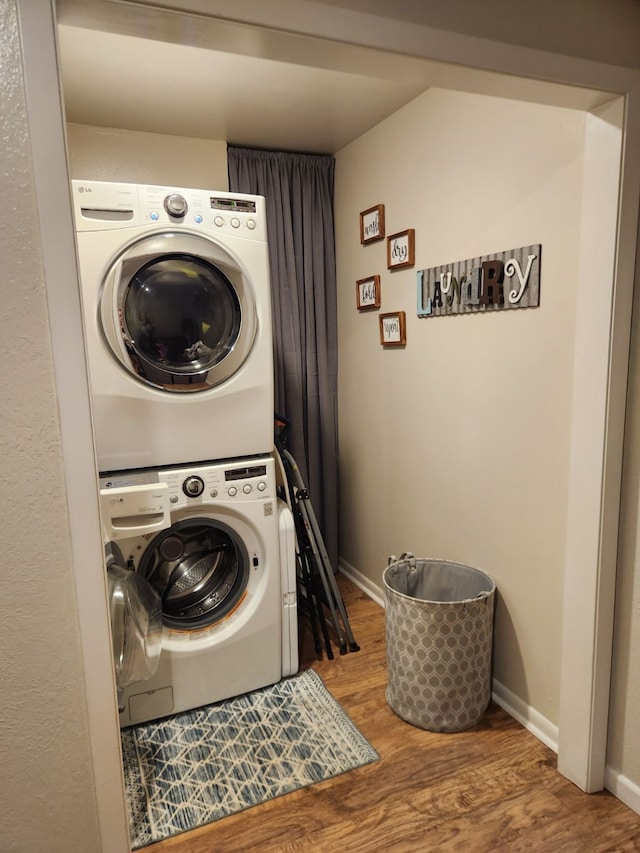 laundry room with stacked washer / dryer and hardwood / wood-style flooring