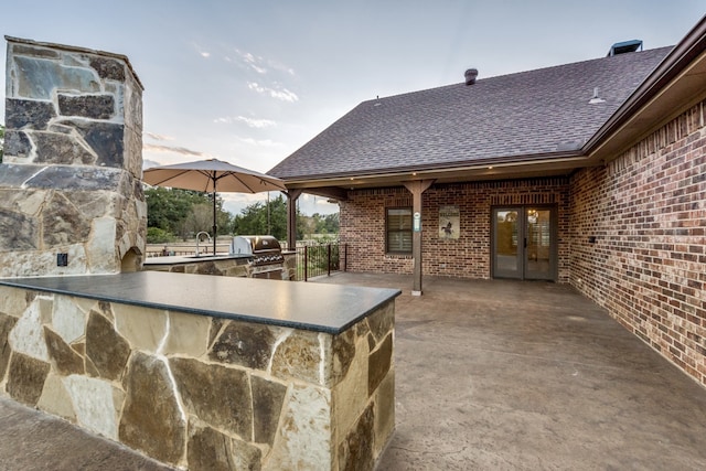 patio terrace at dusk featuring exterior kitchen, sink, and grilling area