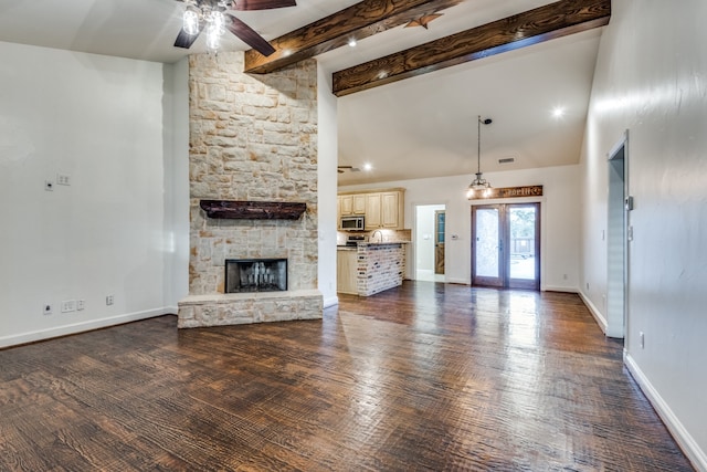 unfurnished living room with french doors, a stone fireplace, lofted ceiling with beams, dark hardwood / wood-style flooring, and ceiling fan