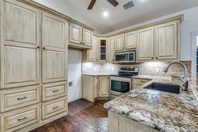 kitchen with dark hardwood / wood-style floors, sink, light stone countertops, vaulted ceiling, and appliances with stainless steel finishes