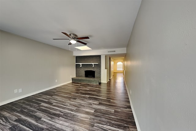 unfurnished living room featuring ceiling fan, dark hardwood / wood-style flooring, and a brick fireplace