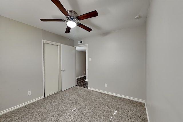 unfurnished bedroom with ceiling fan, a closet, and dark colored carpet