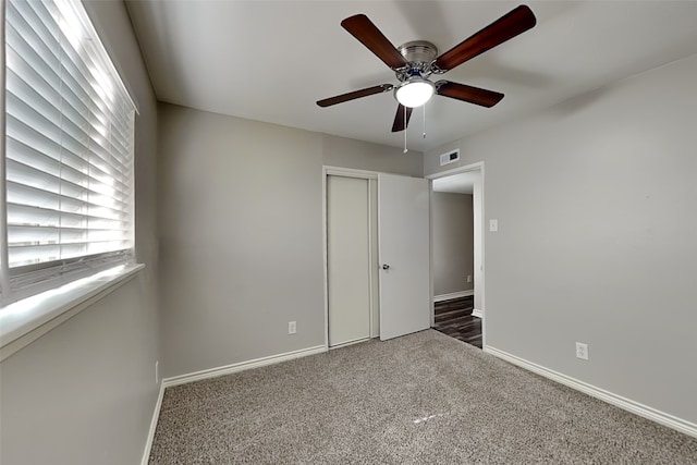 unfurnished bedroom with ceiling fan, a closet, and dark colored carpet