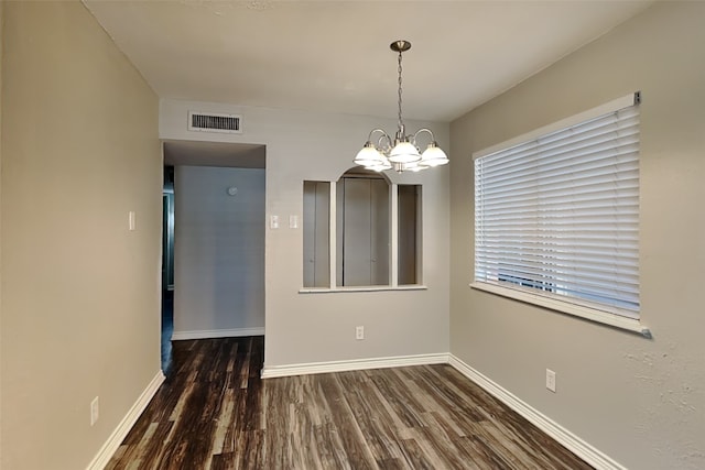 unfurnished dining area featuring dark hardwood / wood-style floors and a chandelier