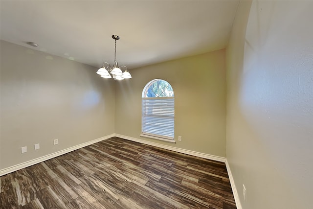 empty room featuring dark hardwood / wood-style flooring and a notable chandelier