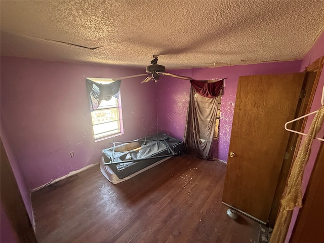 unfurnished bedroom with a textured ceiling, dark hardwood / wood-style floors, and ceiling fan