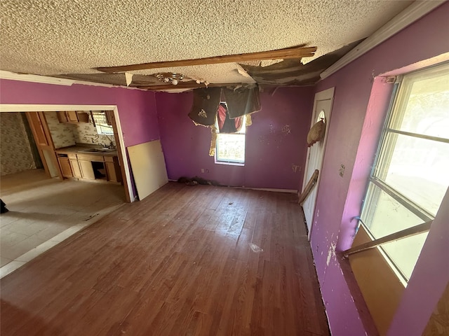 unfurnished living room featuring sink, wood-type flooring, and a textured ceiling