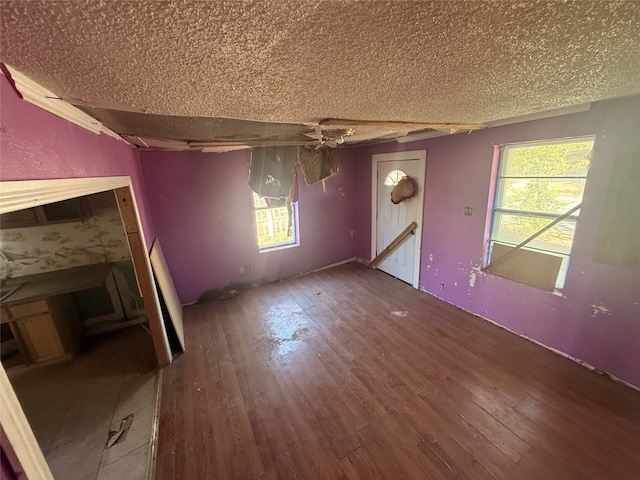 unfurnished living room with hardwood / wood-style floors, a textured ceiling, and ceiling fan