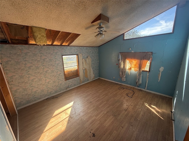 spare room with a textured ceiling, vaulted ceiling, wood-type flooring, and ceiling fan