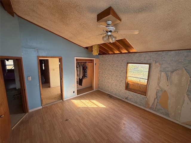 unfurnished bedroom with lofted ceiling, hardwood / wood-style floors, a textured ceiling, and a closet