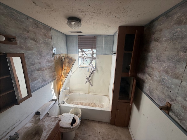 full bathroom featuring washtub / shower combination, a textured ceiling, toilet, vanity, and tile patterned flooring