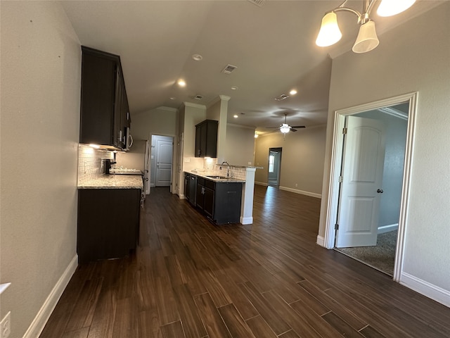 kitchen with dark hardwood / wood-style floors, backsplash, sink, light stone countertops, and vaulted ceiling