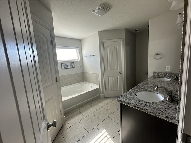 bathroom with vanity, a tub to relax in, a textured ceiling, and tile patterned flooring