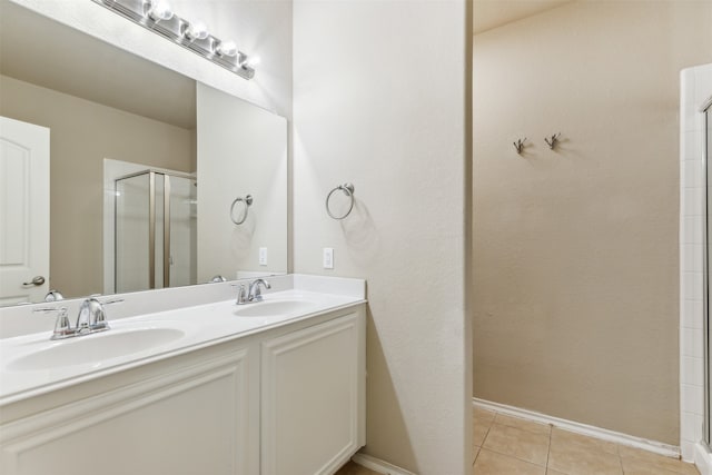 bathroom with a shower with door, vanity, and tile patterned floors