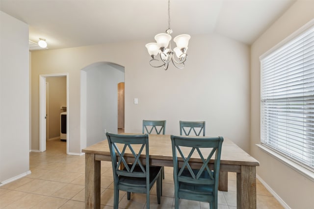 tiled dining area with washer / clothes dryer, a wealth of natural light, a chandelier, and vaulted ceiling