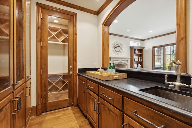 bar with sink, light hardwood / wood-style flooring, and ornamental molding