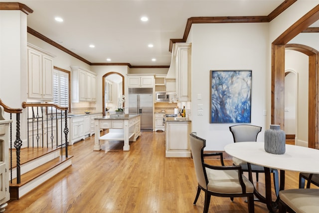 kitchen featuring built in appliances, white cabinetry, light hardwood / wood-style flooring, and a kitchen island