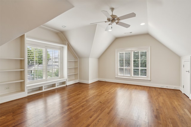 additional living space featuring built in features, wood-type flooring, ceiling fan, and vaulted ceiling