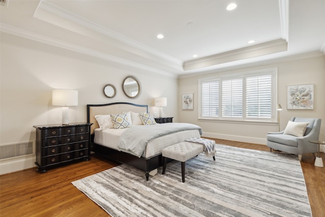 bedroom featuring hardwood / wood-style floors, crown molding, and a tray ceiling