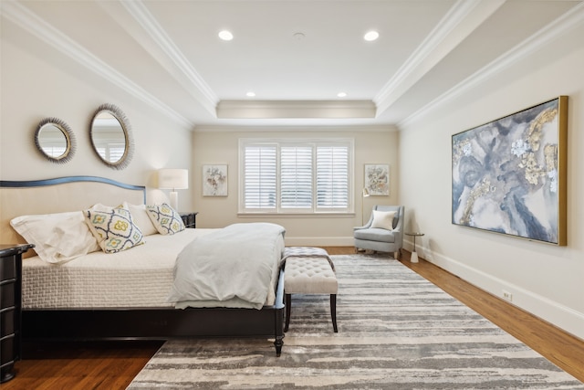 bedroom featuring ornamental molding, wood-type flooring, and a raised ceiling